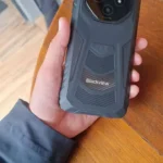 Homem segurando smartphone robusto Blackview preto com câmera circular e textura de fibra de carbono.