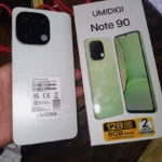 Foto real do celular Umidigi Note 90 branco ao lado da caixa original mostrando 128GB de memória.