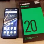 Smartphone Doogee Blade 20 ligado ao lado de sua caixa oficial preta e verde, exibindo a tela inicial e informações de 128GB de memória.