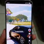 Mão segurando o smartphone Infinix Hot 60 Pro Plus com a tela AMOLED curva ligada exibindo o aplicativo TikTok.