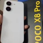 POCO X8 Pro na cor branca ao lado da sua caixa original preta e amarela, destacando o design das câmeras e o acabamento premium.