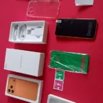 Unboxing completo da imitação do iPhone 17 Pro Max sobre um fundo vermelho, detalhando os acessórios para avaliar se o BML X17 Pro vale a pena.